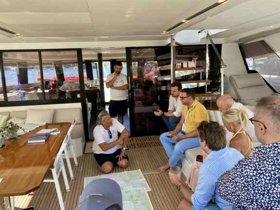 Captain Evan walks a group of DMA brokers through the itinerary in the saloon of catamaran ALEXANDRA II at the Poros yacht show