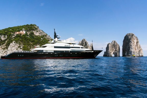 A megayacht lying off the Faraglioni limestone stacks at Capri, Italy