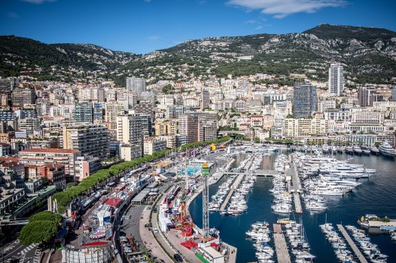 Monaco seen from above Port Hercule, with superyachts, motor boats and sailing yachts berthed along the marina pontoons and the apartment towers of Monte-Carlo and La Condamine rising up the hillside behind